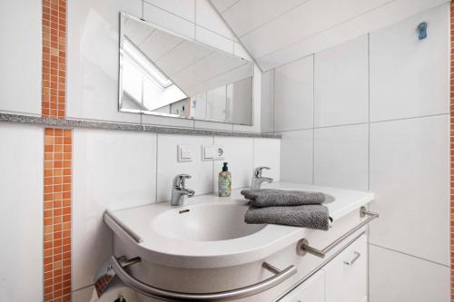 a white bathroom with a sink and a mirror at Haus Bross in Hayingen