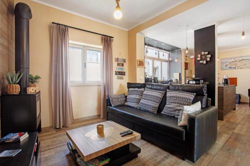 a living room with a black leather couch and a table at Home Away From Home in Peniche