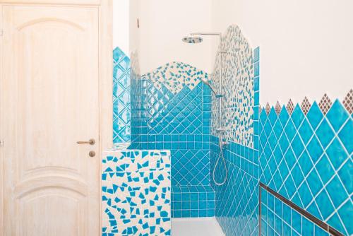 a blue tiled bathroom with a shower and a toilet at Maison Chloe in La Maddalena