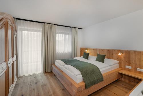a bedroom with a large bed with white sheets and green pillows at Vernalhof Apt Sunnaseit in Sluderno