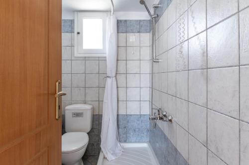a bathroom with a toilet and a window at Anemologio 102 Tinos in Agios Ioannis