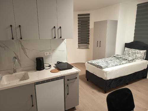 a bedroom with a bed and a kitchen with a sink at City Apartments Göppingen in Göppingen