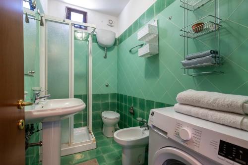 a green bathroom with a sink and a washing machine at Bilocale Valledoria in Valledoria