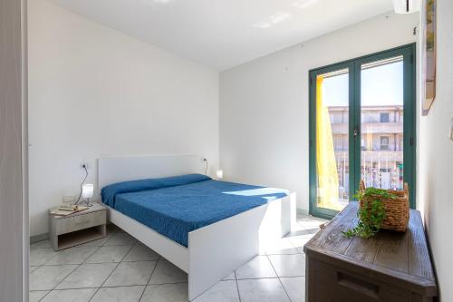 a white bedroom with a bed and a window at Bilocale Valledoria in Valledoria