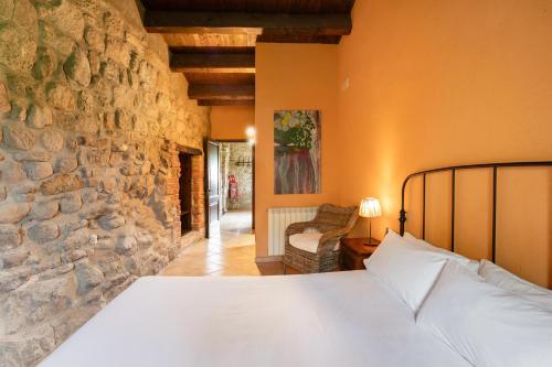 a bedroom with a bed and a stone wall at Casamira in Sagás