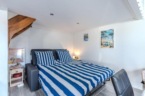 a bedroom with a bed with blue and white stripes at Chalet studio bassin d'Arcachon in La Teste-de-Buch