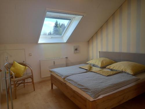 a bedroom with a bed with a window and a chair at Haus Oettinger in Hayingen