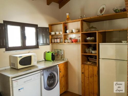 a kitchen with a washing machine and a microwave at Casas Da Lagoa - T2 Norte in Aldeia de Brescos