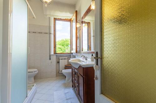 a bathroom with a sink and a toilet and a window at Cottage Casa Luisa in Montalcino
