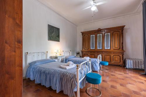 a bedroom with two beds and two blue chairs at Cottage Casa Luisa in Montalcino