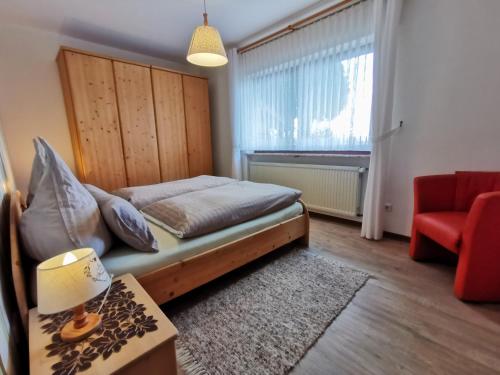 a small bedroom with a bed and a red chair at Zur schönen Aussicht in Schotten