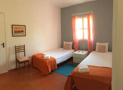 a room with two beds and a chair and a window at Country House With Private Pool in Tavira