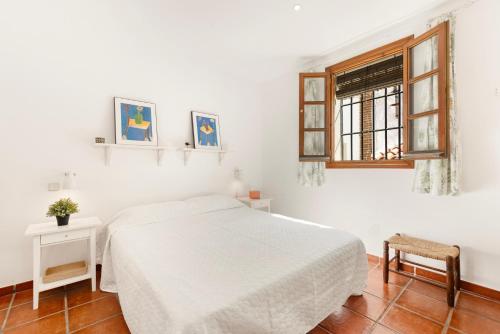 a white bedroom with a bed and a window at Casa Limón in Vélez-Málaga