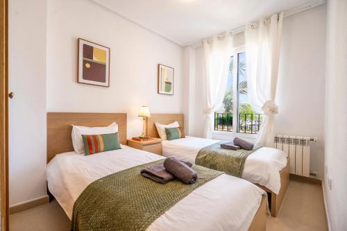 two beds in a room with a window at Casa Albatros - Poolside Retreat in Torre-Pacheco