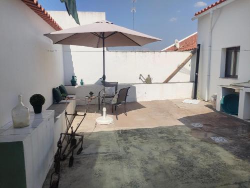 a patio with a table and an umbrella at Casa da Avó Cândida in Granja
