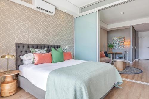 a bedroom with a large bed with colorful pillows at Backup-Powered Trendy City Balcony Apartment in Cape Town