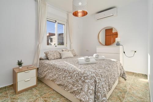 a white bedroom with a bed and a mirror at Almijarahouse in Nerja