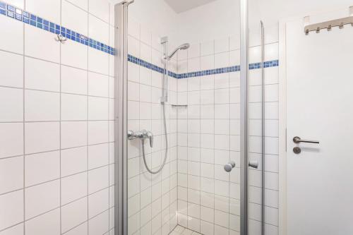 a shower in a bathroom with white tiles at Fewo Zur Piste in Willingen