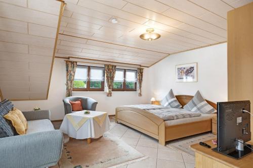 a bedroom with a bed and a couch and a tv at Gieringer in Oberharmersbach