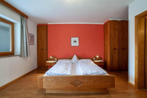 a bedroom with a bed and a red wall at Camping Passeier Arnika in Saltusio