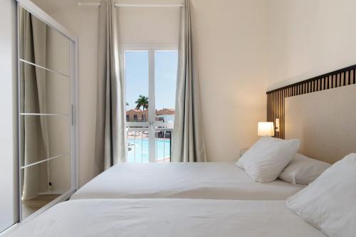 a bedroom with a white bed and a balcony at Oasis Pool View in Maspalomas