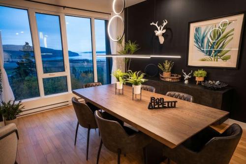 a dining room with a wooden table and chairs at 206 - Bright Modern Condo - Pool and River View in Baie-Saint-Paul