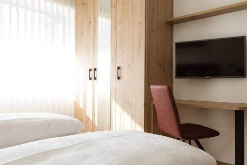 a bedroom with a bed and a chair and a tv at Kleon 2 in Rifiano
