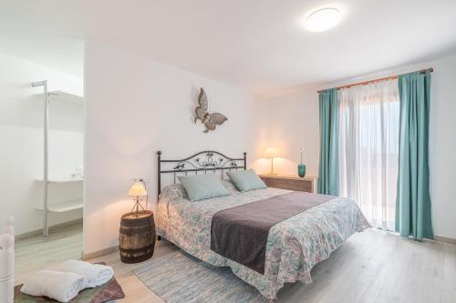 a white bedroom with a bed and a window at Ca sa Tia Lluisa in Santanyi
