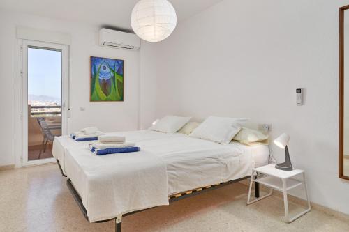a white bedroom with a large bed and a chair at Casa Bellota in Torrox