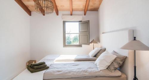 a white bedroom with a large bed with a window at Finca Sa Real in Cala Millor