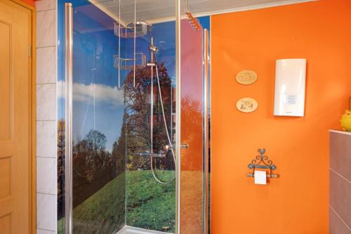 a shower in a bathroom with an orange wall at Finnhütte Hohe Klinge Trusetal in Brotterode