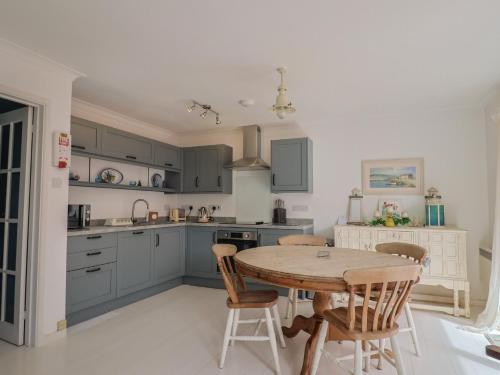 a kitchen with blue cabinets and a wooden table at 1 Bay View Court in Lyme Regis