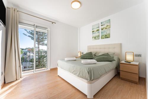 a white bedroom with a bed and a window at Apartment Mijas Sun and Beach in Sitio de Calahonda