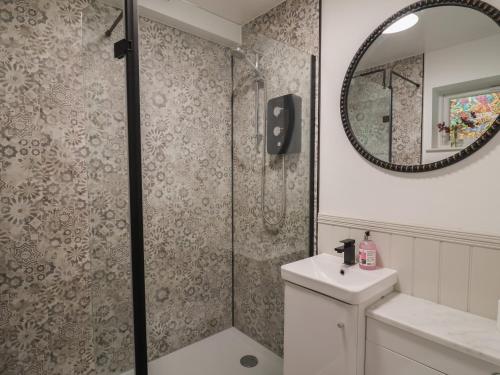 a bathroom with a shower and a sink and a mirror at 1 Bay View Court in Lyme Regis