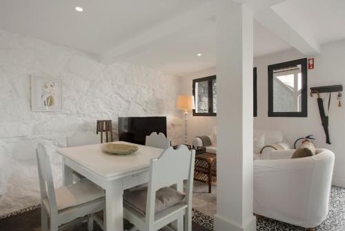 a white dining room with a white table and chairs at The Village Loft in Caniço