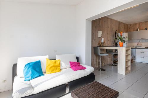 a living room with a white couch with colorful pillows at Studio Cosy Climatisé, Cap Bretron in Capbreton