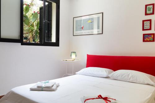 a bedroom with a red headboard and a white bed at Nido in Monte Petrosu