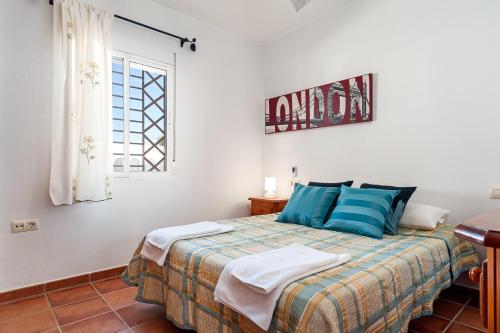 a bedroom with a bed with blue pillows and a window at Casa - 2 Mar y Sombra in Barbate
