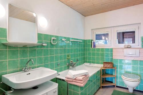 a green tiled bathroom with a sink and a toilet at Haus Doktor Saeltzer in Lenzkirch