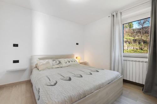 a white bedroom with a large bed and a window at Cà De Qualì in Costa Volpino
