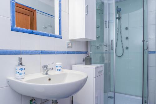 a white bathroom with a sink and a shower at Appartamento Murena 1 in La Maddalena