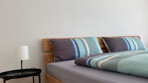 a bed with two pillows and a table with a lamp at Bei Dörflingers in Klettgau