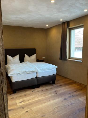 a bedroom with a large bed with white sheets and a window at Bio Bausewein - No.2 Apartment in Iphofen