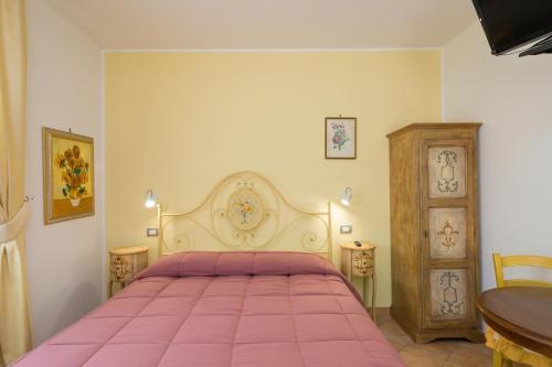 a bedroom with a pink bed and a wooden cabinet at Il Girasole - Cappero in Venturina Terme