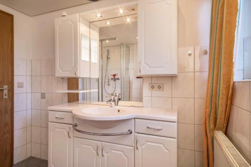 a white bathroom with a sink and a mirror at Ferienwohnung Marschall in Achberg