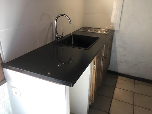 a kitchen with a black sink and a stove at Le Mas in Arles-sur-Tech