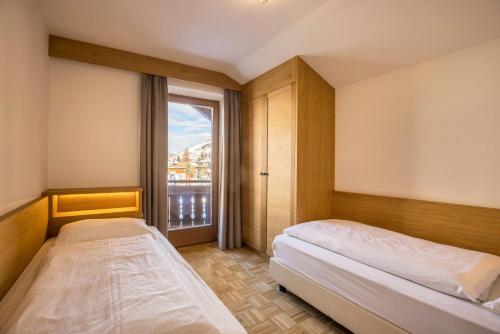 a bedroom with two beds and a large window at Rosalpina Apt 4 in San Vigilio Di Marebbe