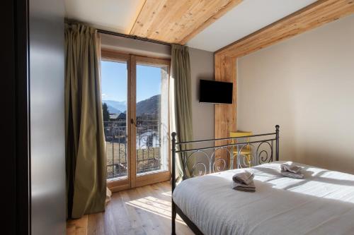 a bedroom with a bed and a large window at Casa Ronden Mortirolo in Mazzo di Valtellina