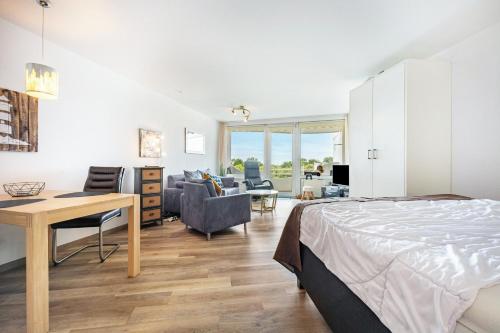 a bedroom with a bed and a desk and chairs at Apartementhaus Lord Nelson in Cuxhaven