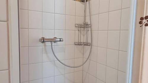 a shower with a hose in a white tiled bathroom at Ferienhaus Burg Celle in Celle